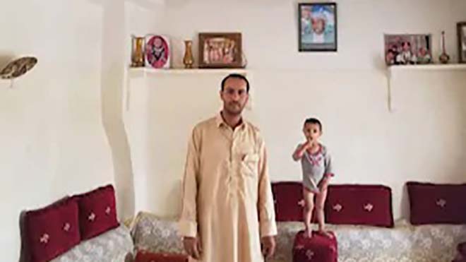 أمين الهبال يقف في غرفة المعيشة في منزل عائلته القديم ، حيث سقط جزء من السقف